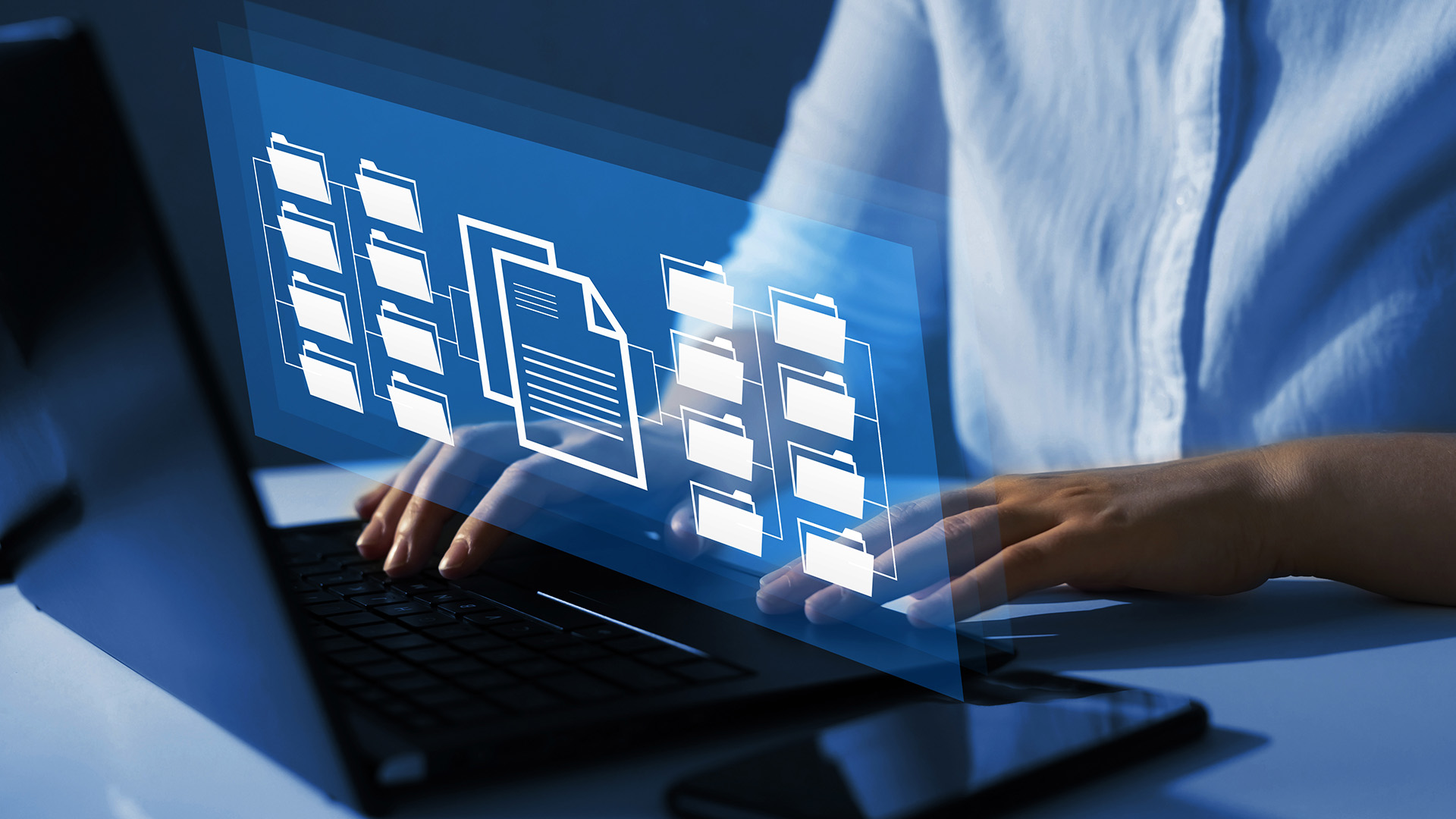Female risk manager types on laptop with floating documents surrounding the area as graphic treatment